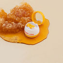 Sweetums Flavored Lip Balm Honey with honeycomb and golden syrup on a light background.