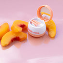 Sweetums Flavored Lip Balm Peach with sliced peaches on a glossy pink surface.