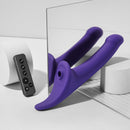 Strap-on-me Multi Orgasm Vibrating Dildo Medium Purple positioned next to its intuitive remote on a modern surface.