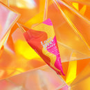 Love To Love Love Me Tender Cotton Candy Massage Oil tube against a colorful background.