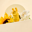 Camtoyz Clitoral Thumper Bumble Bee peeking among sunflowers and flowers, showcasing its playful design.