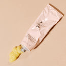 Sex Au Naturel Vulva Balm Soothing Moisturizer tube with balm squeezed out on a beige background
