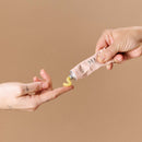 A hand dispensing Sex Au Naturel Vulva Balm Soothing Moisturizer into another hand, showcasing its rich texture.
