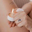 Bijoux Indiscrets Slow Sex Massage Candle being lit, showcasing its warm, inviting glow for intimate moments.