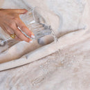 Pouring water over Splash Blanket The OG Medium Waterproof Champagne showcasing its waterproof feature.