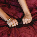 Hands pressing on the waterproof Splash Blanket The OG Medium Waterproof Throw Moon Blood, showcasing its durability.