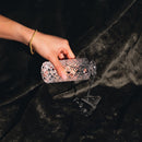 A hand pouring water from a crystal glass onto the Splash Blanket Furlush Large Waterproof Throw Black.