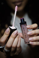 Eye of Love Matchmaker Pink Pulse Pheromone pH Lip Stain applicator and gloss container held by a person.
