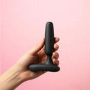Lovense Glint Touch Responsive Vibrating Butt Plug Black in hand against a pink background.