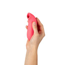 Hand holding the Dame Aer Air Pulse Suction Vibrator Coral, designed for clitoral stimulation with air pulse technology.