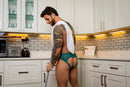 Male Power Ripple Moon Jock Teal S/M worn by a man in a kitchen, showcasing its bold design and supportive fit.