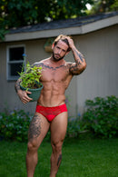 Male Power Sassy Lace Bikini Solid Pouch Navy XL worn by a muscular man holding a plant in a garden setting.