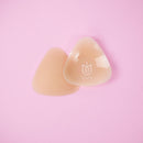 Uva Triangular Nipple Covers Caramel against a pink background, showcasing their triangular shape and warm caramel tone.