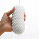 Tenga 3DX Flow Male Masturbator being held with water droplets, showcasing its unique design and texture.