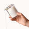 Dame Massage Oil Candle Wild Lust being held with melting wax, showcasing its luxurious design and soothing essence.