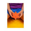 Cute Little Fuckers Starsi Palm Vibrator Coral held in hands, featuring a playful star shape in warm coral silicone.