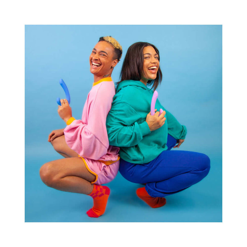 Two joyful individuals holding the Cute Little Fuckers Jix Vibrator Lavender, showcasing vibrant colors and playful expressions.