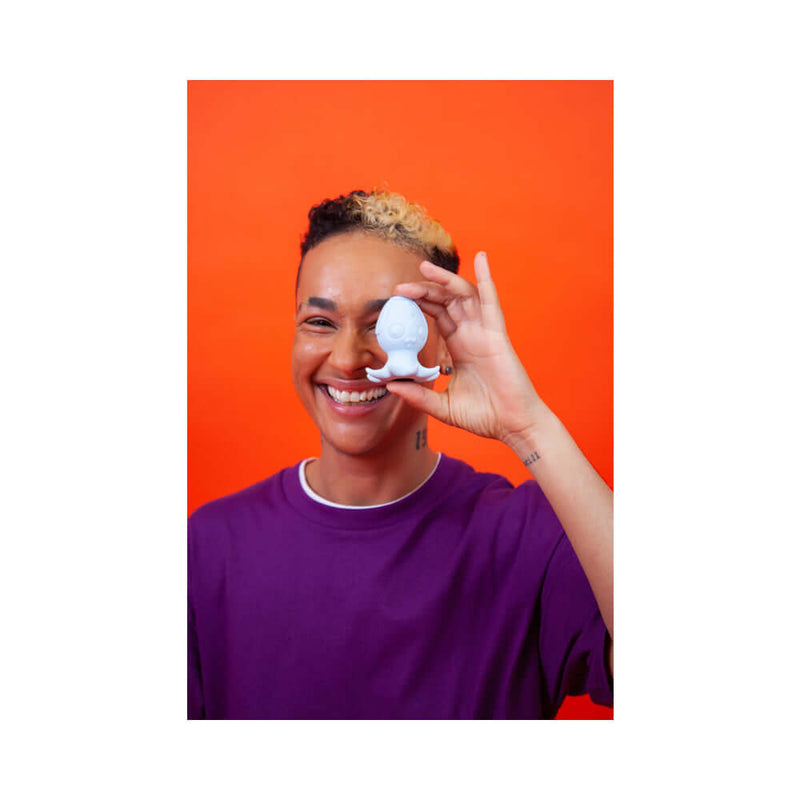 Cute Little Fuckers Princette Puppypus Platinum held by a smiling person against an orange background.