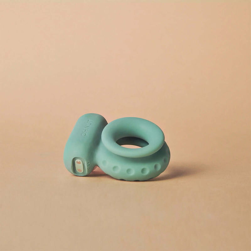 Ohnut Vibrating Penis Ring Jade on a soft surface, showcasing its ergonomic design and powerful motor for enhanced pleasure.
