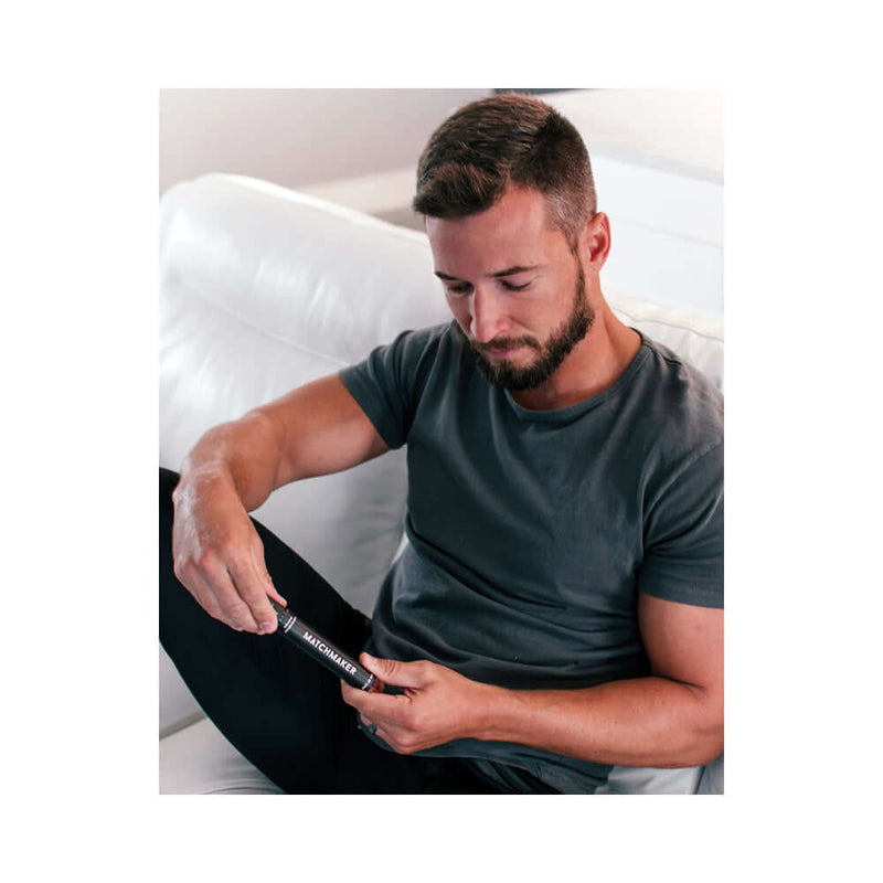 A man sitting on a couch using Eye of Love Matchmaker Black Diamond Attract Her Pheromone 10 ml fragrance.