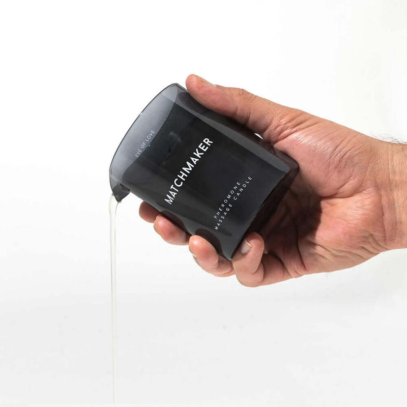 Eye of Love Matchmaker Black Diamond Attract Her Massage Candle being poured from a hand, revealing its elegant design.