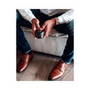 Eye of Love Confidence Attract Her Pheromone Massage Candle held by a man in stylish brown shoes.