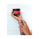 Eye of Love One Love Attract Him Pheromone Massage Candle in hand with elegant nails and rings.