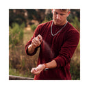Man applying Eye of Love Romantic Attract Her Pheromone Parfum 10 ml outdoors in casual attire.