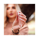 Woman holding Eye Of Love One Love Attract Him Pheromone Parfum 10 Ml in a sunny outdoor setting.