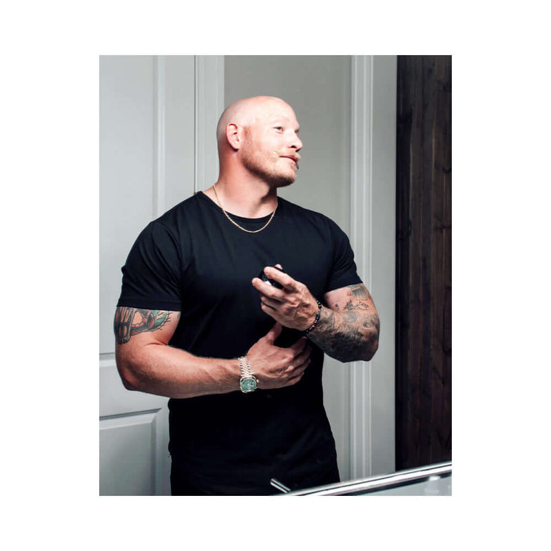 Man applying Eye of Love Matchmaker Black Diamond Attract Her Parfum 1 Oz in a modern bathroom setting.