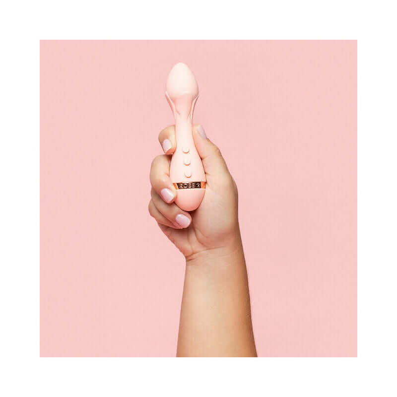 Hand holding the VUSH Rose 2 Precision Bullet Vibrator against a pink background.