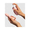 Hands holding VUSH Clean Queen Intimate Accessory Spray 2.7 Oz and a pink pleasure product.