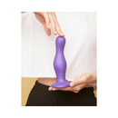Strap-on-me Dildo Plug Curvy Small Purple held by a person, showcasing its unique shape and vibrant color.