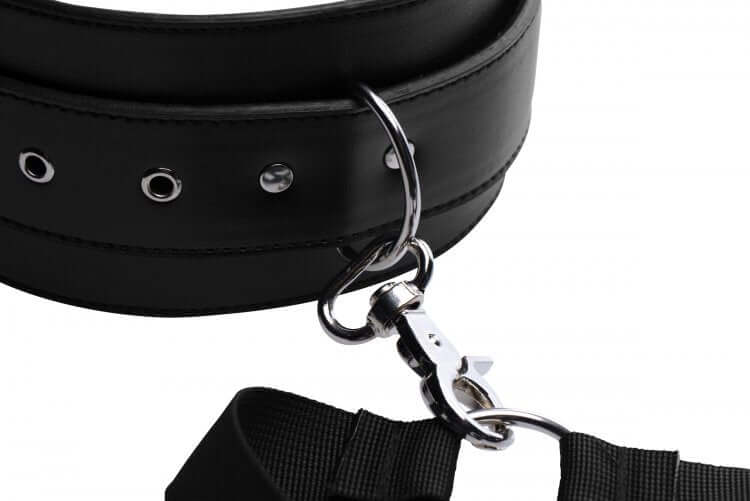 Adjustable black leather thigh harness with metal clips and grommets for bondage restraint system.