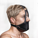 Image of STRICT Mouth Harness with Ball Gag Black worn by a model, showcasing the sleek design and muzzle style.