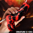 Hell Hound Squirting Silicone Penis Enhancer Red held in hand, showcasing its unique design and texture.