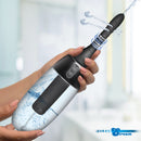 CleanStream XL Spinning Automatic Enema Bulb Black in hand with water spray for intimate hygiene.