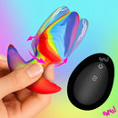 Bang Rotating and Vibrating Silicone Butt Plug Rainbow in hand with remote control, showcasing rainbow colors and rotation.