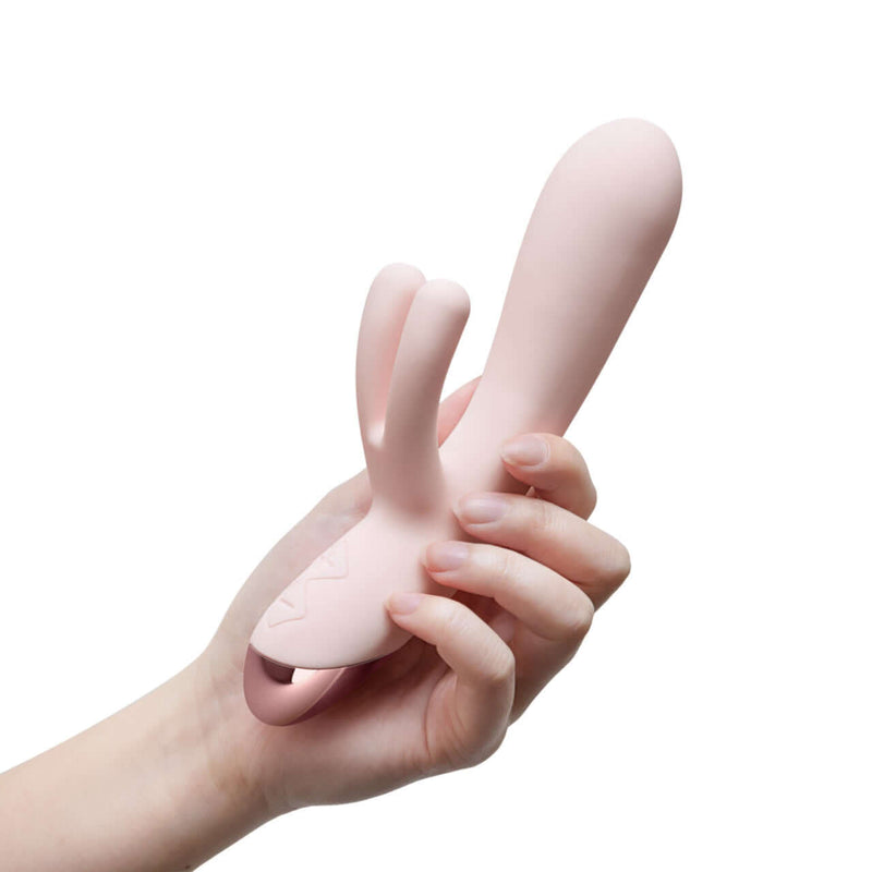 Hand holding Blush Elora Pink Rabbit Vibrator, showcasing its sleek Silicone shaft and dual rabbit arms for luxury stimulation.