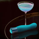 Oh My Gem Fierce Blue Topaz rechargeable vibrator beside a cocktail, highlighting sensuality and self-exploration.