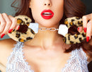 Temptasia Furry Leopard Adjustable Wrist Cuffs showcased in a daring pose with a model holding them.