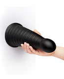 b-Vibe Cone 10 Inch Tapered Ribbed XXL Suction Cup Dildo held against a wall, showcasing its sleek design and ribbed texture.