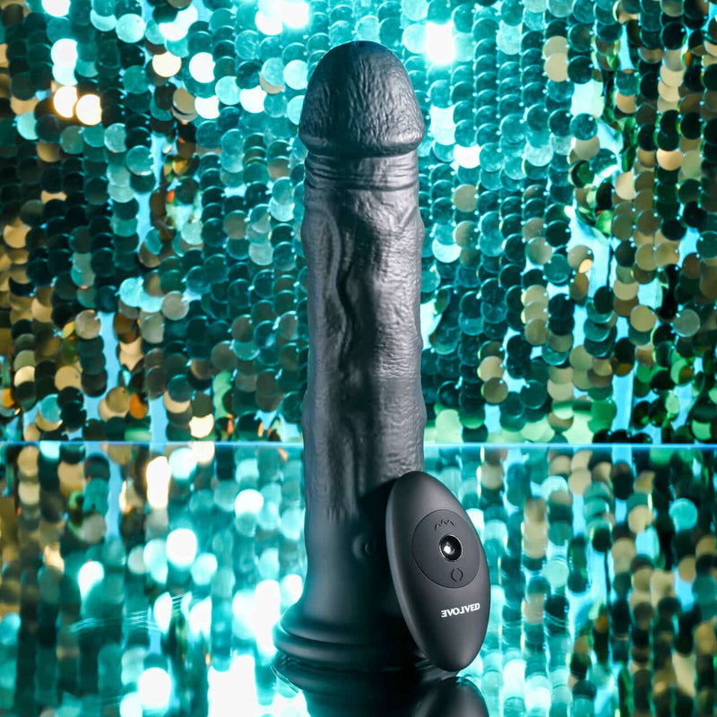 Evolved Black Thunder Internal Massager with Beads and Remote Control against a glittery background.