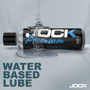JOCK Premium Water Based Lubricant 8 Oz bottle with liquid lubricant pouring out on a smooth surface.
