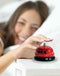 Woman ringing red "Ring for Sex" desktop bell with playful smile.