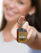 Woman holding a novelty "Suck a Bag of Dicks" keychain with colorful design, perfect for adding fun to keyrings.