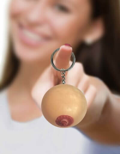 Smiling woman holding a Super Fun Key Chain featuring a squishy boob design, perfect for adding humor to keyrings.