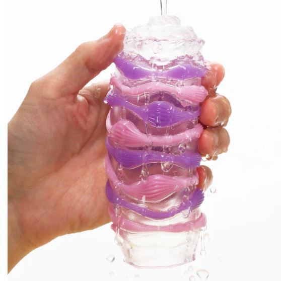 Tenga Arte Drape Stroker held in hand with water flowing over its textured surface.
