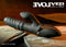 Evolved Ring It Home Silicone Rechargeable Vibrator with dual clitoral stimulator in black on textured surface.