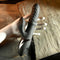 Black silicone rechargeable vibrator with clitoral stimulator showcased on a hand against a textured rock background.